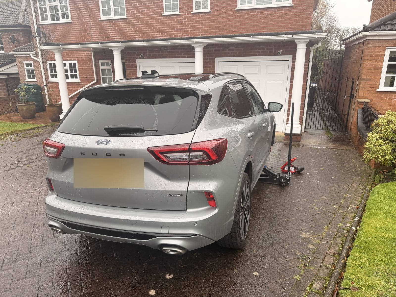 SUV raised on a jack on a house driveway for tyre fitting